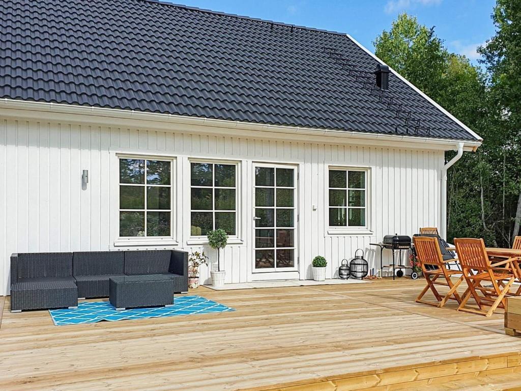 un patio con un sofá negro en una terraza de madera en Holiday home NORRTÄLJE IX, en Norrtälje