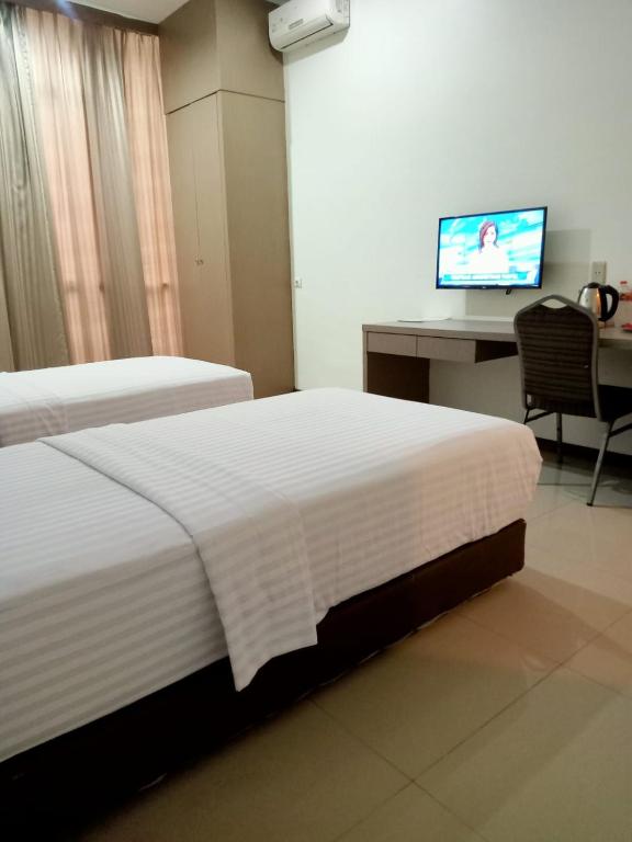 een hotelkamer met 2 bedden, een bureau en een televisie bij Putra Mulia Hotel Medan in Medan