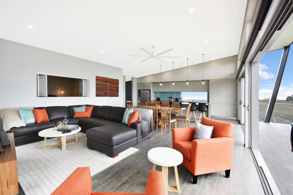 a living room with a black couch and orange chairs at Palkana in Wentworth Falls