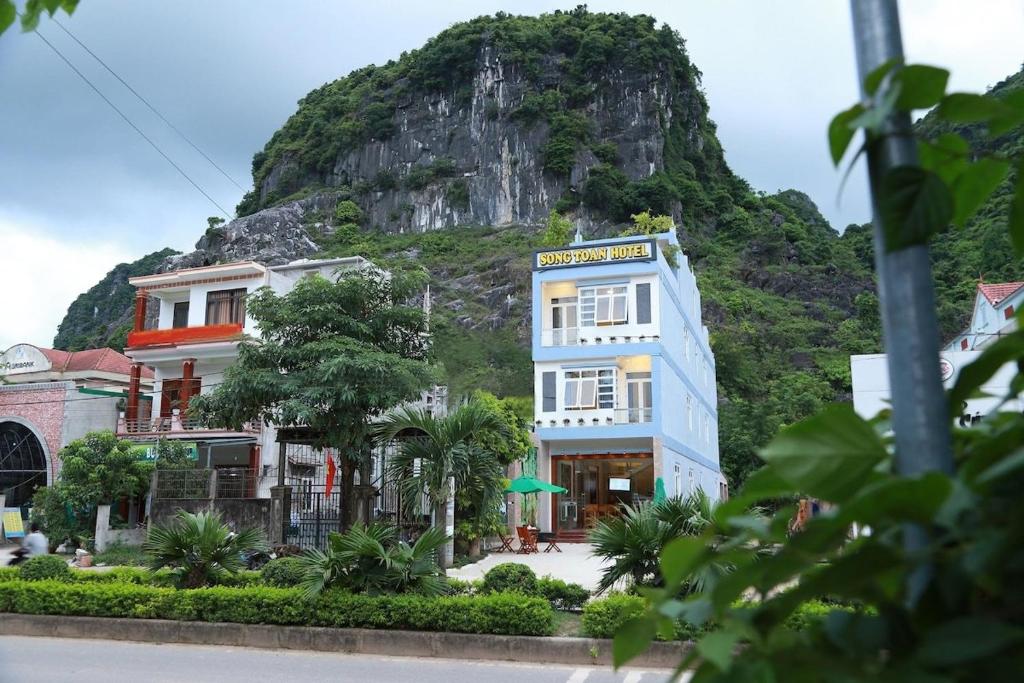 a building with a mountain in the background at Song Toan Hotel in Phong Nha