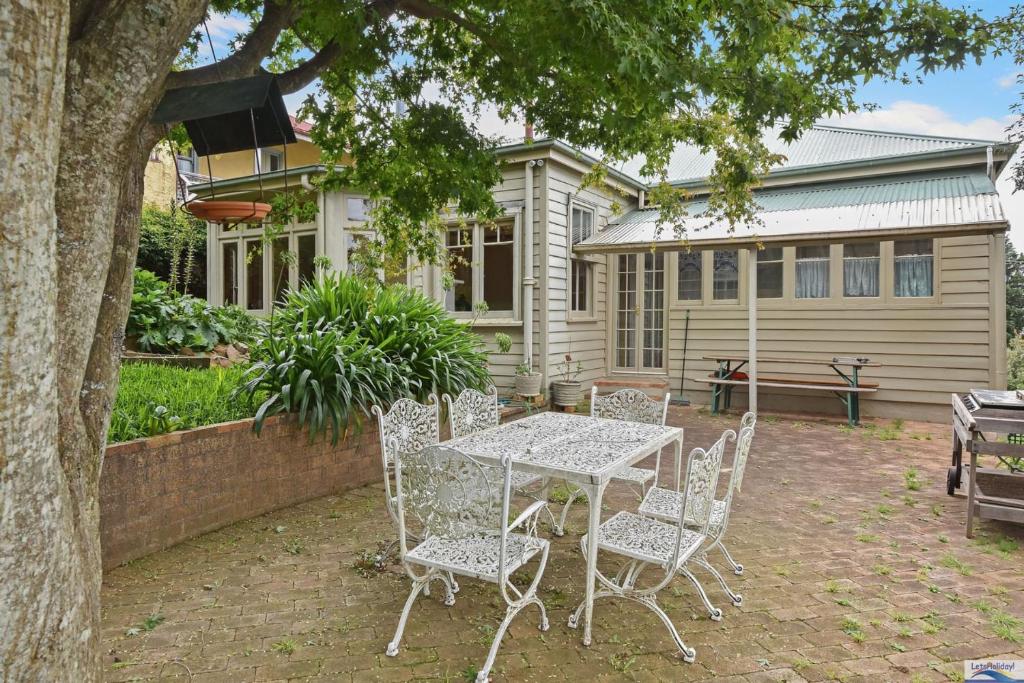 una mesa y sillas frente a una casa en Idlehour Cottage, en Katoomba