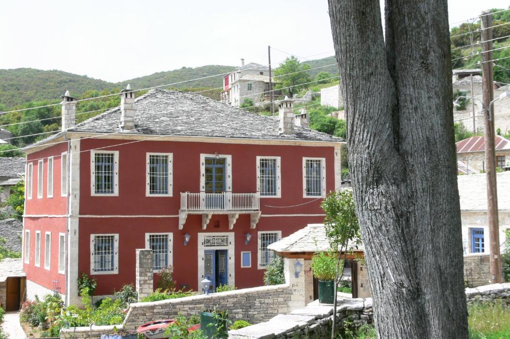 une maison rouge avec un balcon en face de celle-ci dans l'établissement Porfyron, à Áno Pediná