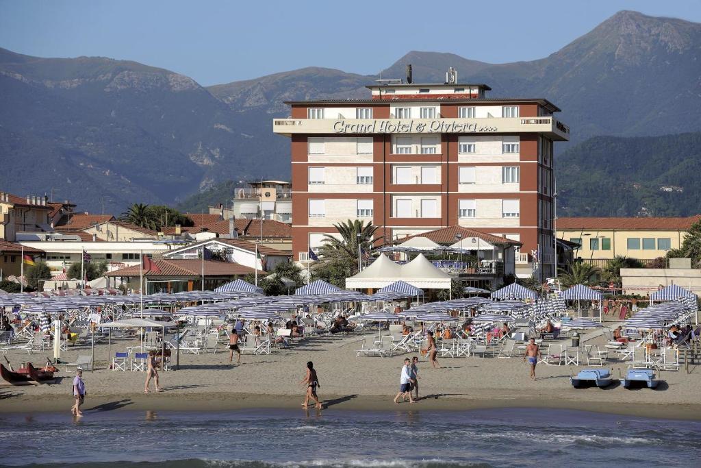 a group of people on a beach with a hotel at Grand Hotel & Riviera in Lido di Camaiore