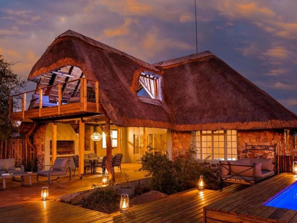uma casa com telhado de palha e piscina em Simbavati Mvubu Cottage em Timbavati Game Reserve