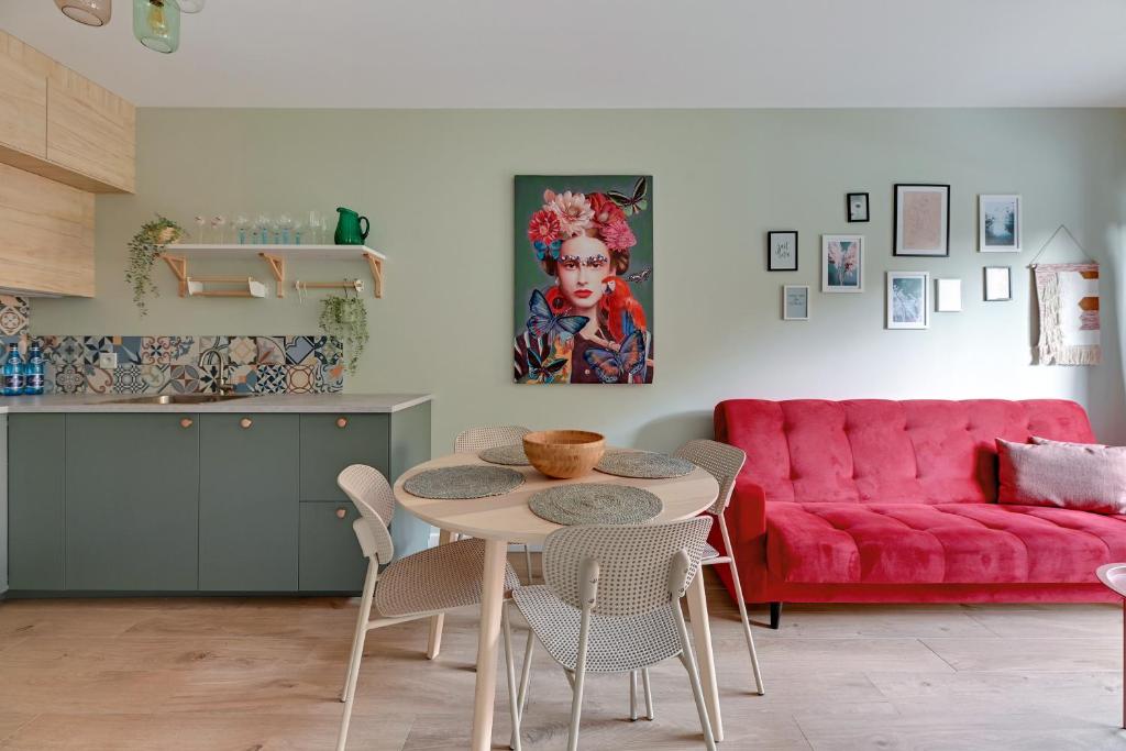 a living room with a table and a red couch at Downtown Apartments Riverside Dwie Motławy in Gdańsk
