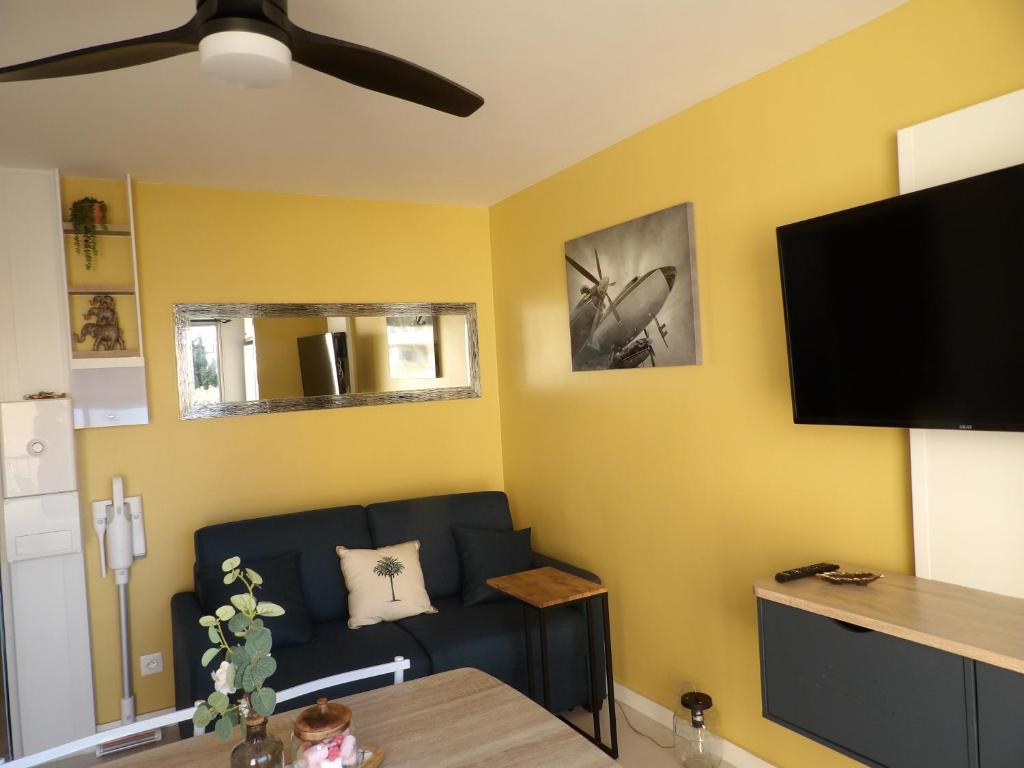 un salon avec un canapé bleu et une télévision à écran plat dans l'établissement Cosy studio au bord de la plage, à Gruissan