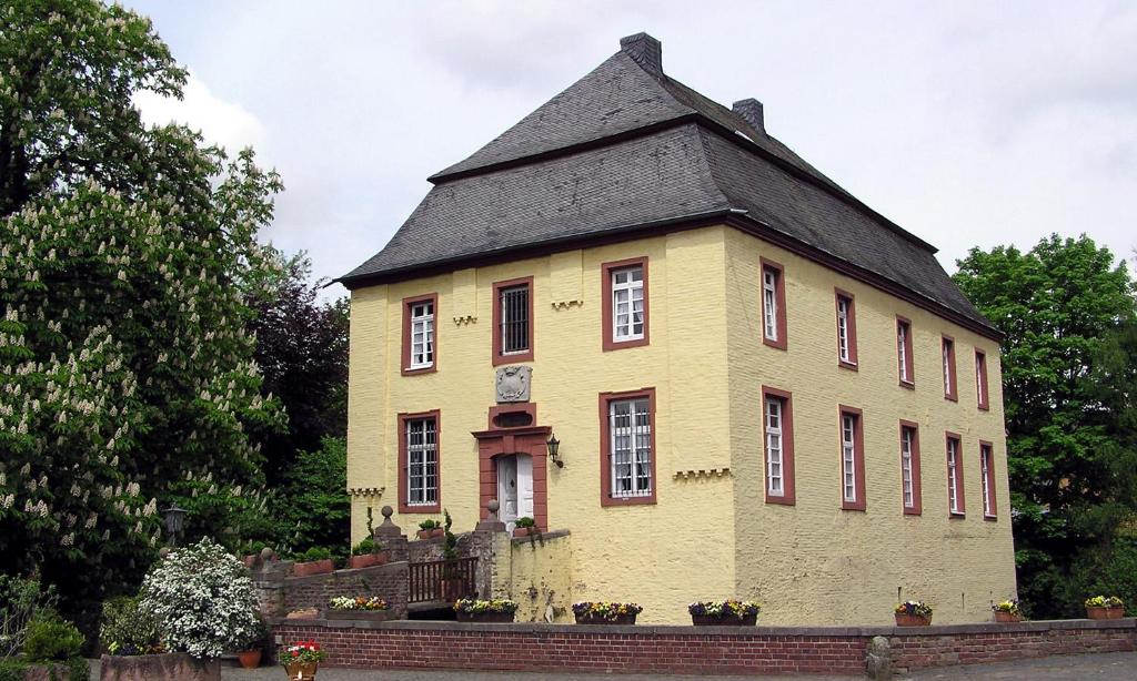 een oud geel gebouw met een zwart dak bij Charmante Ferienwohnungen auf Reitstall Wasserburg Anstel - ein Ort zum Wohlfühlen und Entspannen in Rommerskirchen