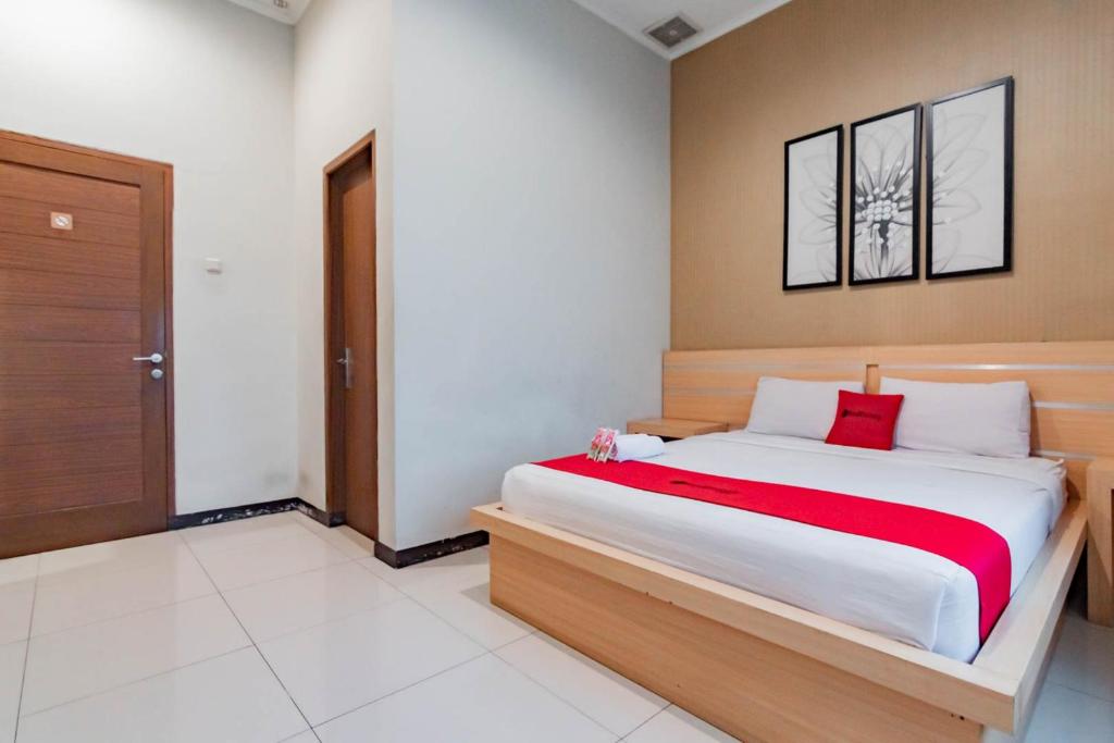 a bedroom with a large bed with a red blanket at RedDoorz near Lembang Park & Zoo 2 in Lembang
