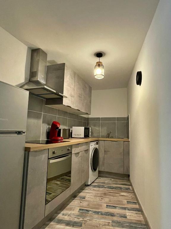 une cuisine équipée d'appareils électroménagers en acier inoxydable et d'un lave-linge/sèche-linge dans l'établissement Draguignan, centre ville wifi jolie deco, à Draguignan