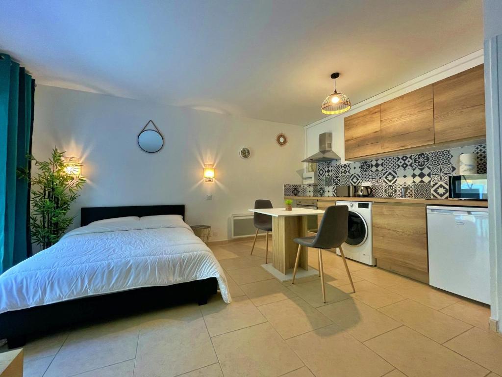 a bedroom with a bed and a table and a kitchen at Draguignan, centre ville wifi jolie deco in Draguignan