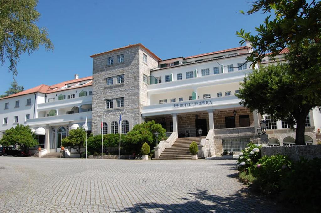 a large white building with a staircase in front of it at Hotel Urgeirica in Nelas