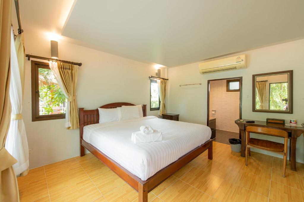 a bedroom with a bed and a desk and a bed at Karaboon Wellness in Phitsanulok