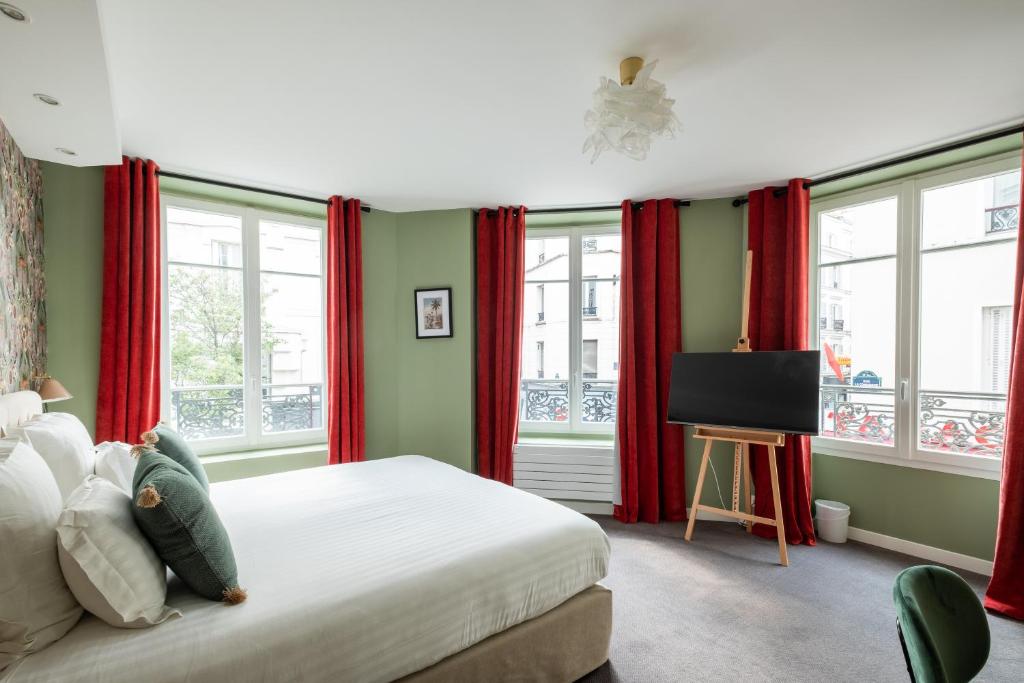 a bedroom with red curtains and a bed with a television at Hôtel Des Batignolles in Paris