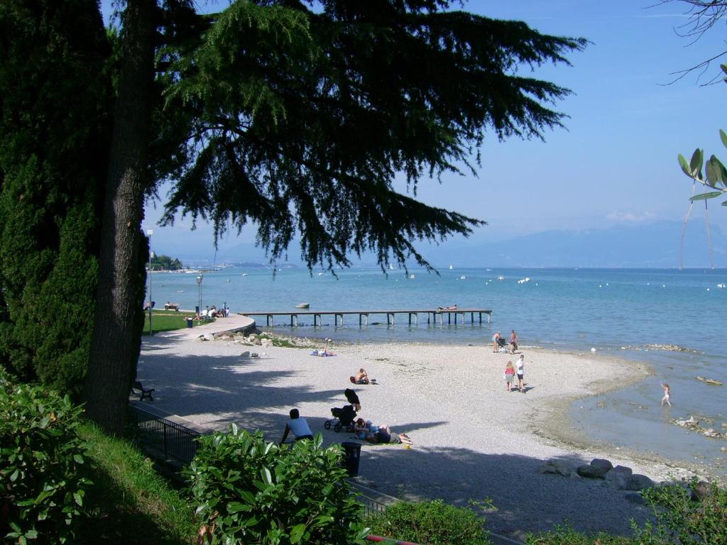 people on a beach with a pier in the water at Camping Bella Italia in Peschiera del Garda