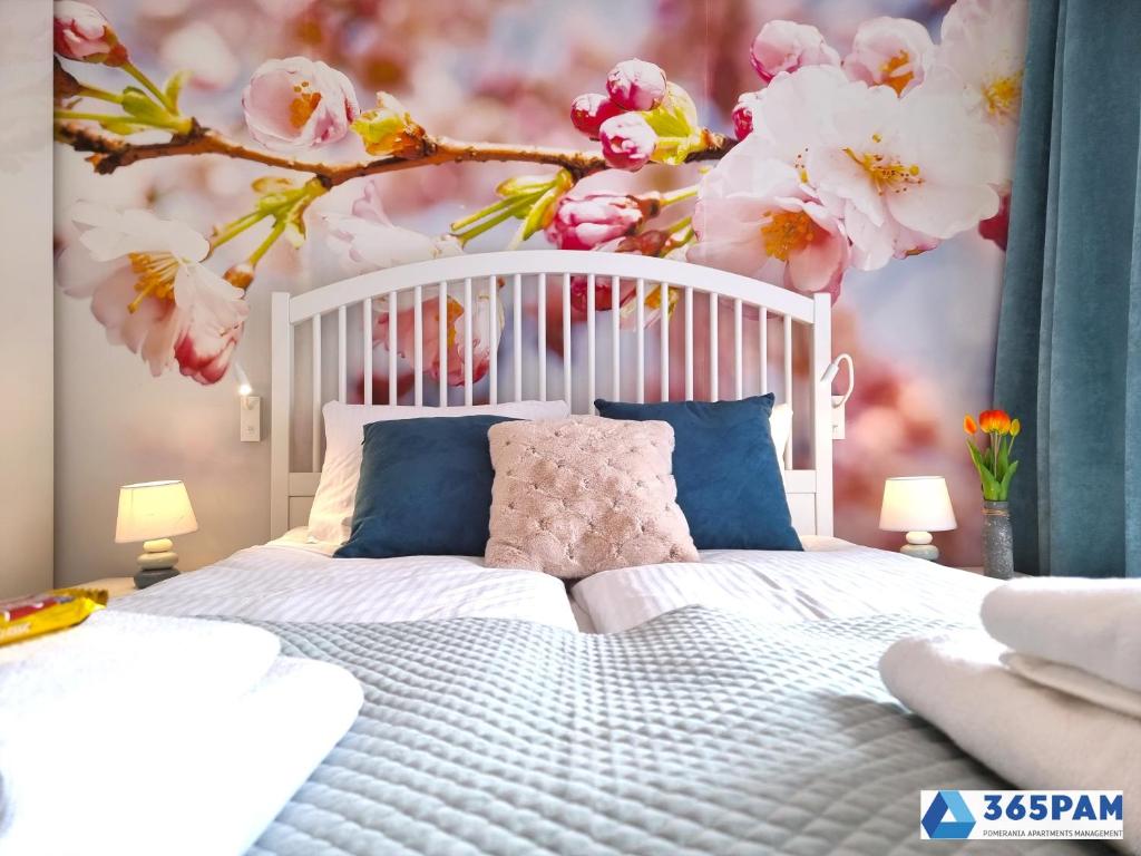 een slaapkamer met een wit bed met een tak van bloemen bij Perła Pomorza Mielno - 365PAM in Unieście