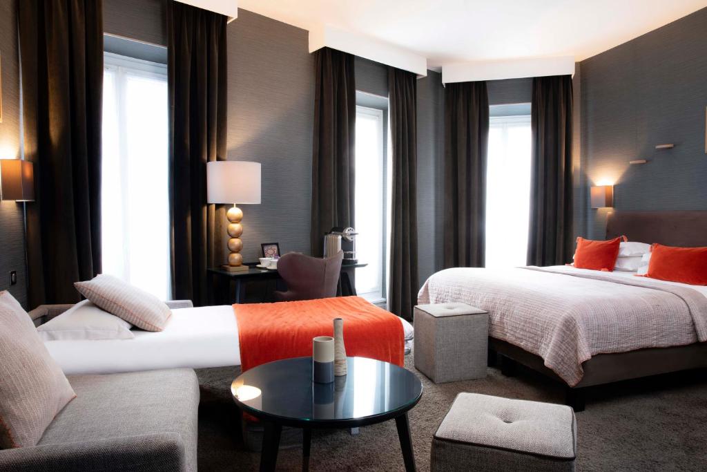 a hotel room with two beds and a couch at Hôtel Plaza Étoile in Paris