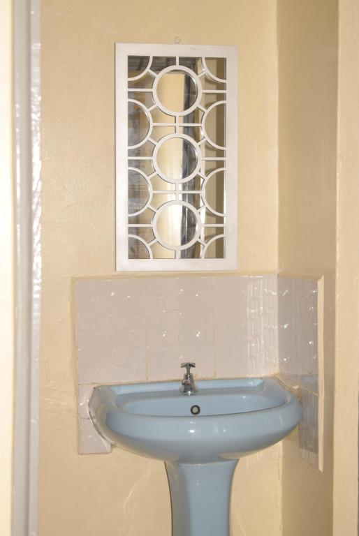Kakamega的住宿－Beautiful 1BR with Wi-Fi & secure parking，一间带水槽和彩色玻璃窗的浴室
