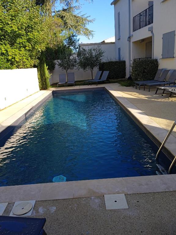 une piscine avec de l'eau bleue devant un immeuble dans l'établissement le clos du ventoux, à Malaucène