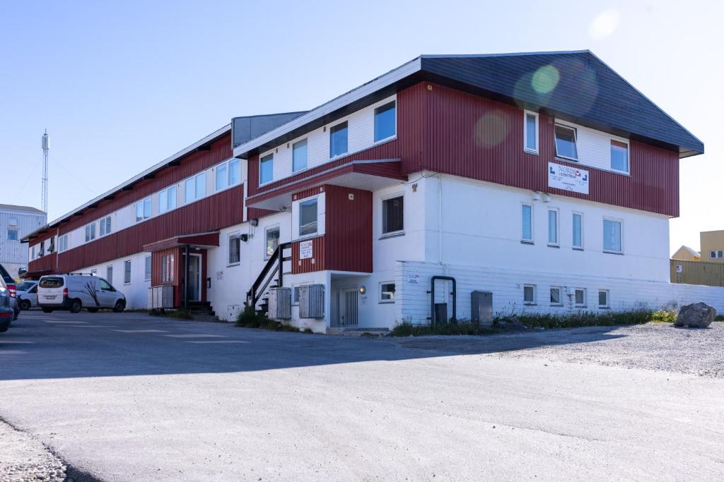 a large red and white building next to a parking lot at Nordbo in Centrum in Nuuk