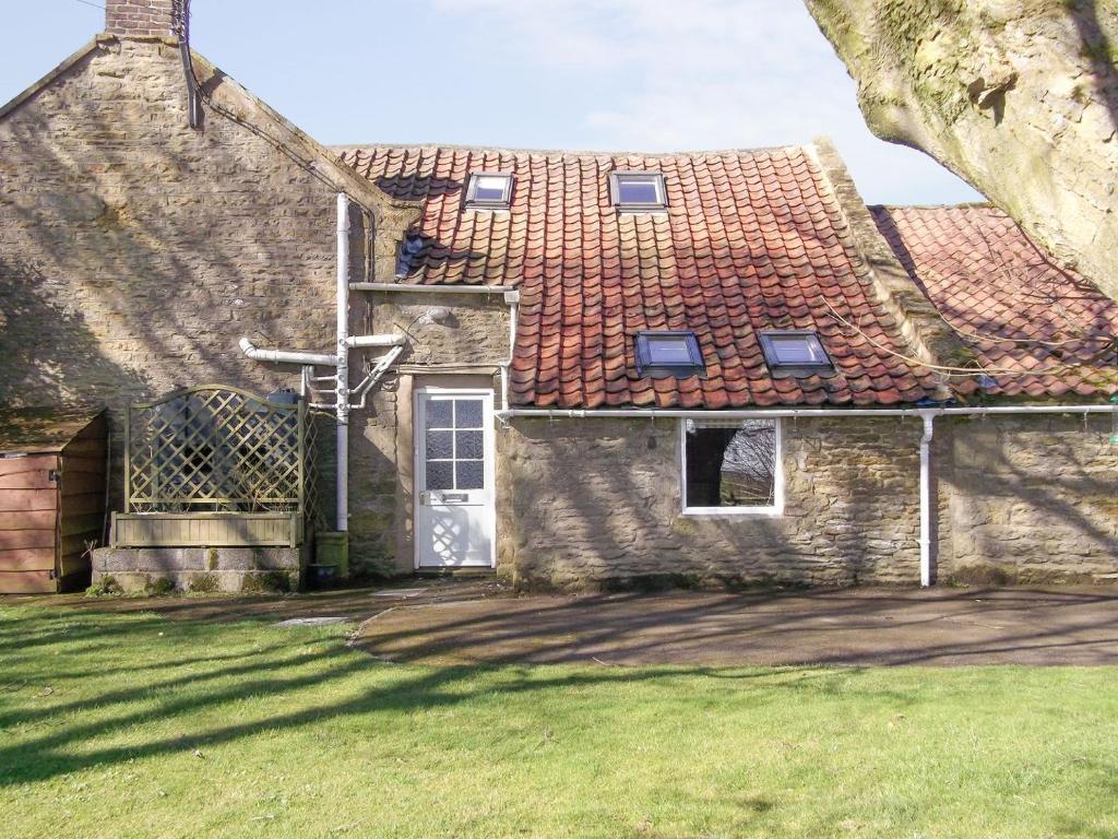 an old stone house with a door and a grass yard at The Grooms Cottage in Hackness