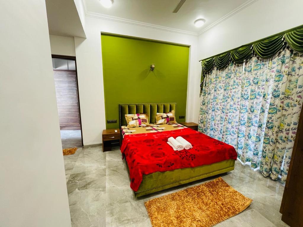 een slaapkamer met een rood bed en een groene muur bij White Tulip in Lonavala