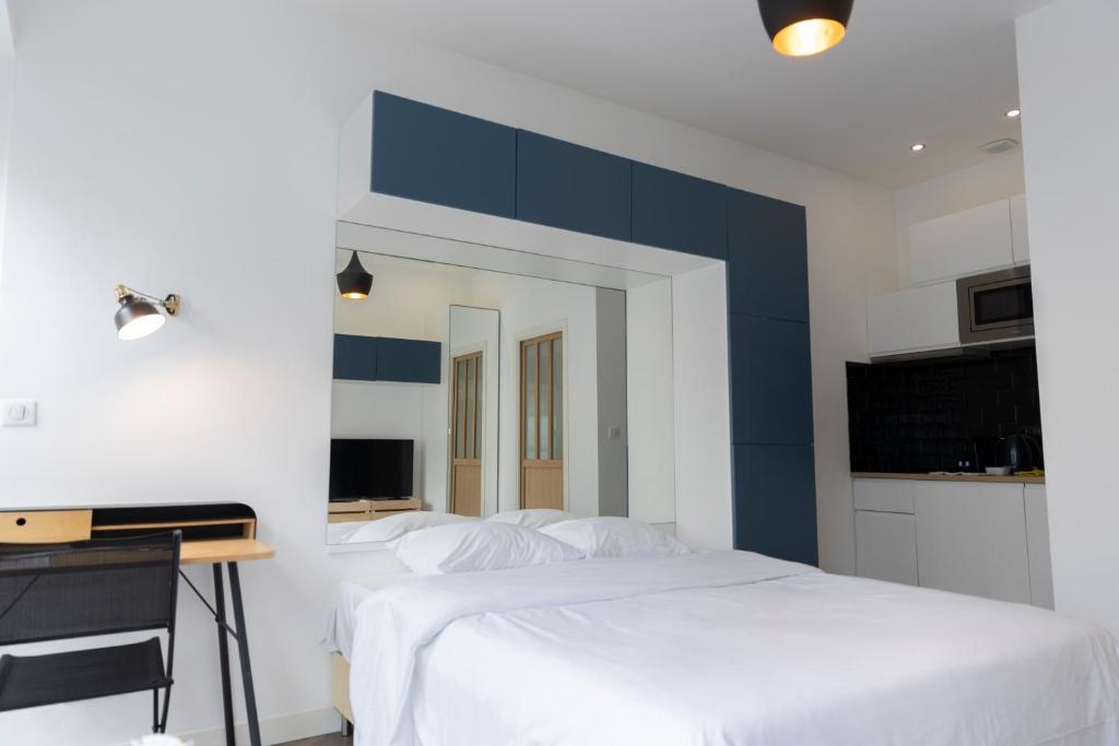 a bedroom with two beds and a desk with a tv at Studio moderne et confort au centre ville in Metz