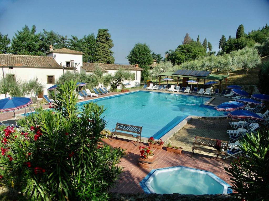 una gran piscina con sillas y sombrillas en Villa Farmhouse with swimming pool in Chianti, en Grassina