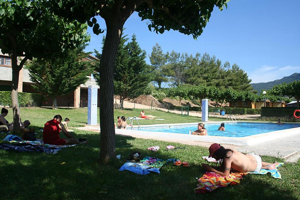 un grupo de personas sentadas en el césped cerca de una piscina en Montsant Park Camping & Bungalow, en Ulldemolins