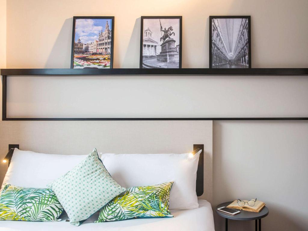 a shelf above a bed with some pictures on it at ibis Brussels Centre Chatelain in Brussels