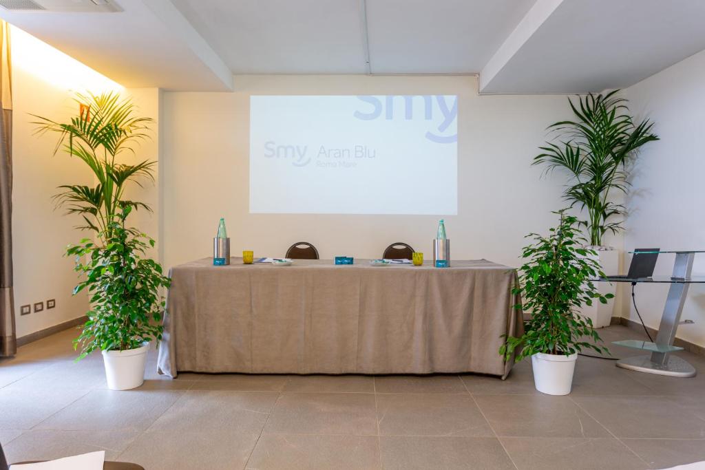 a table in a room with two potted plants at Smy Aran Blu Roma Mare in Lido di Ostia