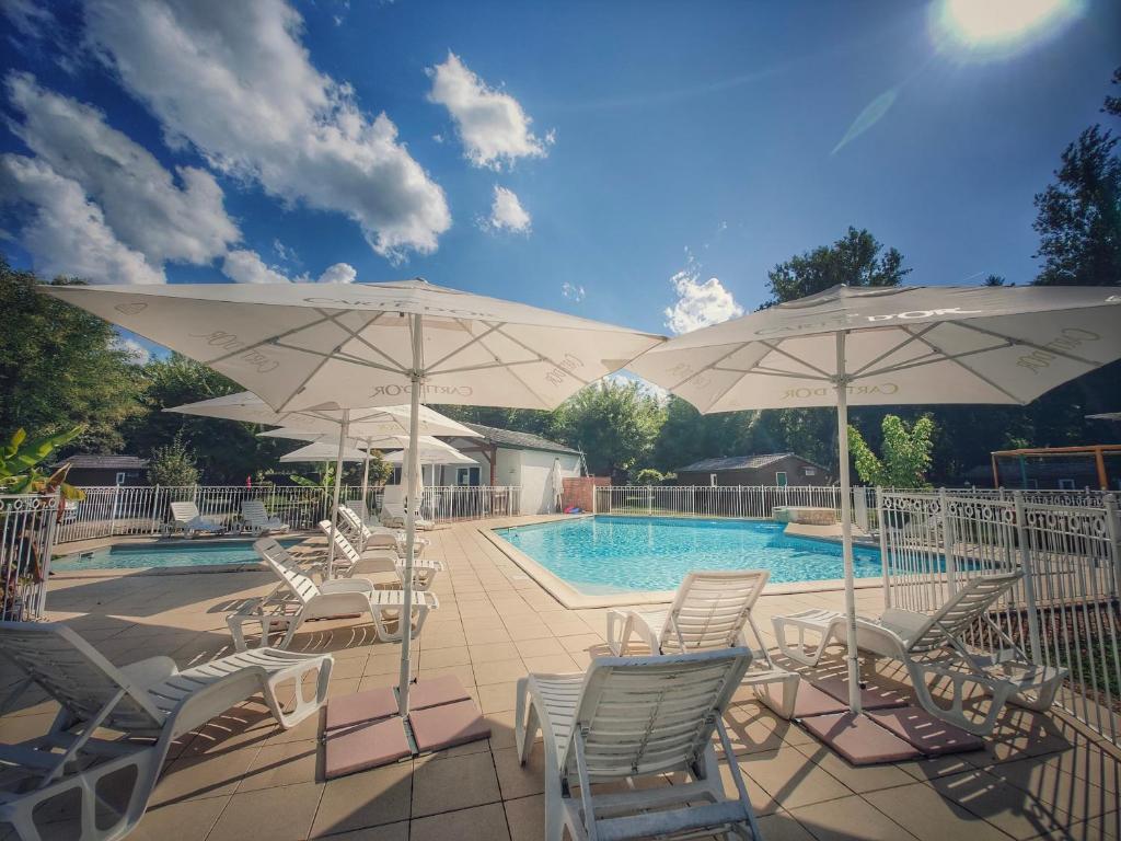 a group of chairs and umbrellas next to a pool at hôtel gites le clos du moulin in Terrasson-Lavilledieu
