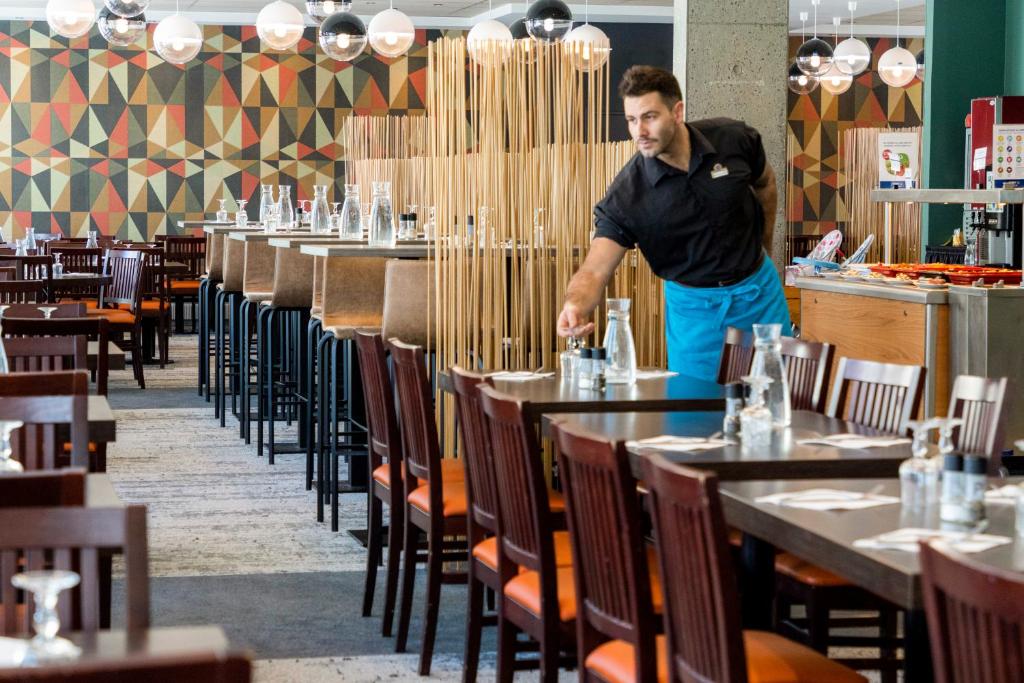 a man standing in a restaurant with tables and chairs at Hôtel Club mmv Le Flaine *** in Flaine