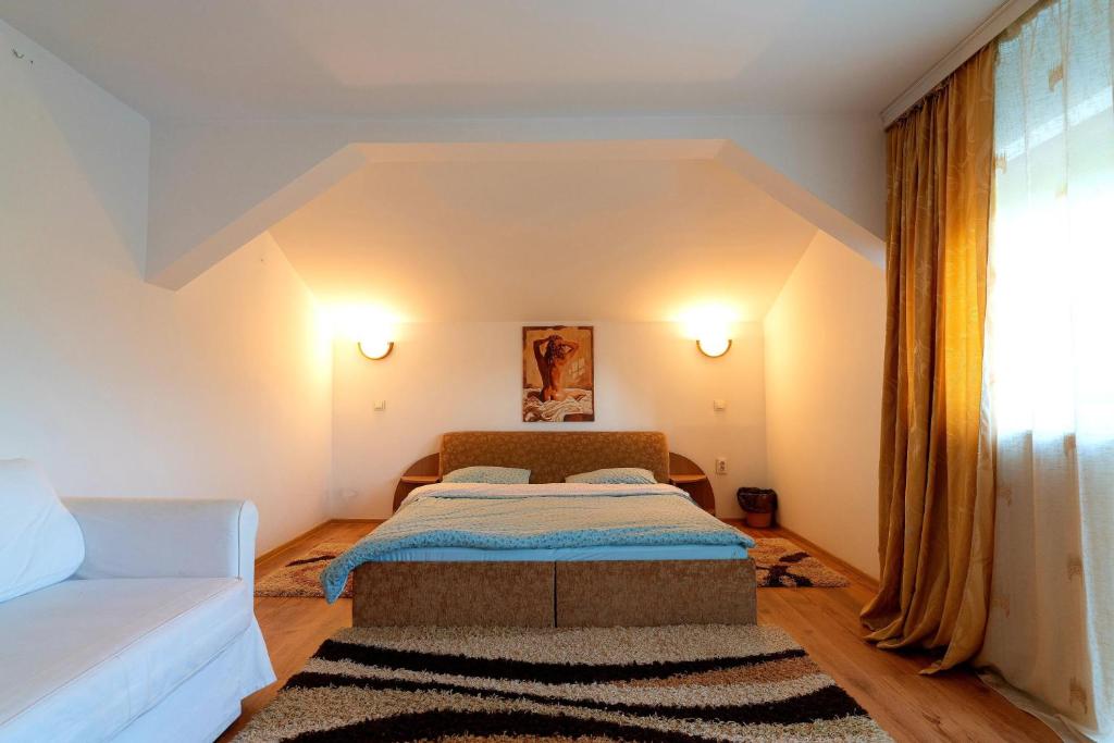 a small bedroom with a bed and a couch at Casa de vacanta Isabelle in Comarnic