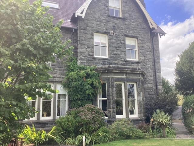 a large brick house with white windows and bushes at Brynffynnon Boutique Bed and Breakfast in Dolgellau