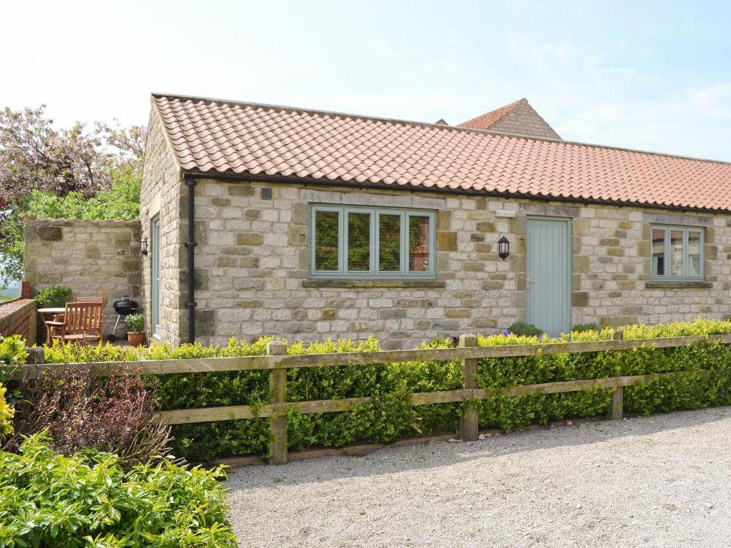 a stone cottage with a wooden fence in front of it at The Wests in Lastingham