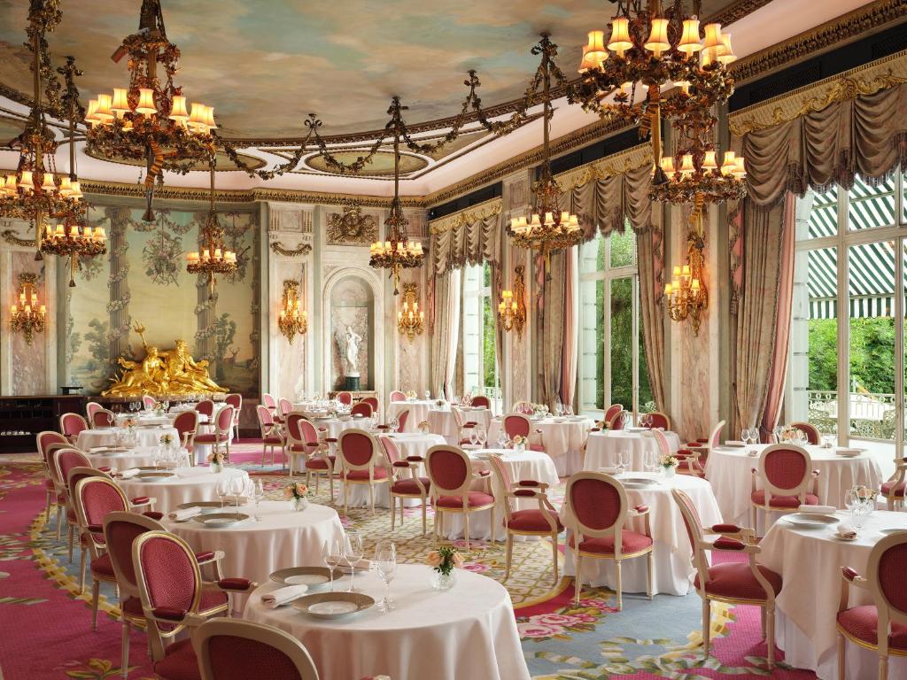 a dining room with white tables and chairs and chandeliers at The Ritz London in London
