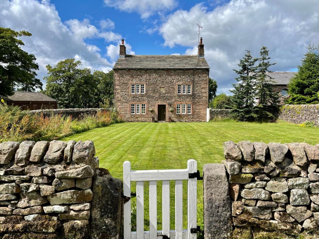 an old stone house with a white fence in front of it at Marl Hill House in Clitheroe