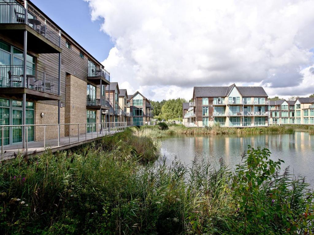 a row of apartment buildings next to a body of water at Apartment 3 in South Cerney