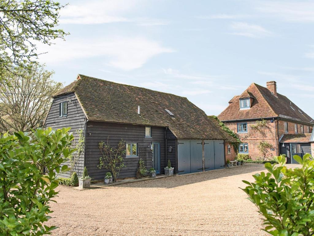 an old barn with a house in the background at Woolhouse Barn in Hunton