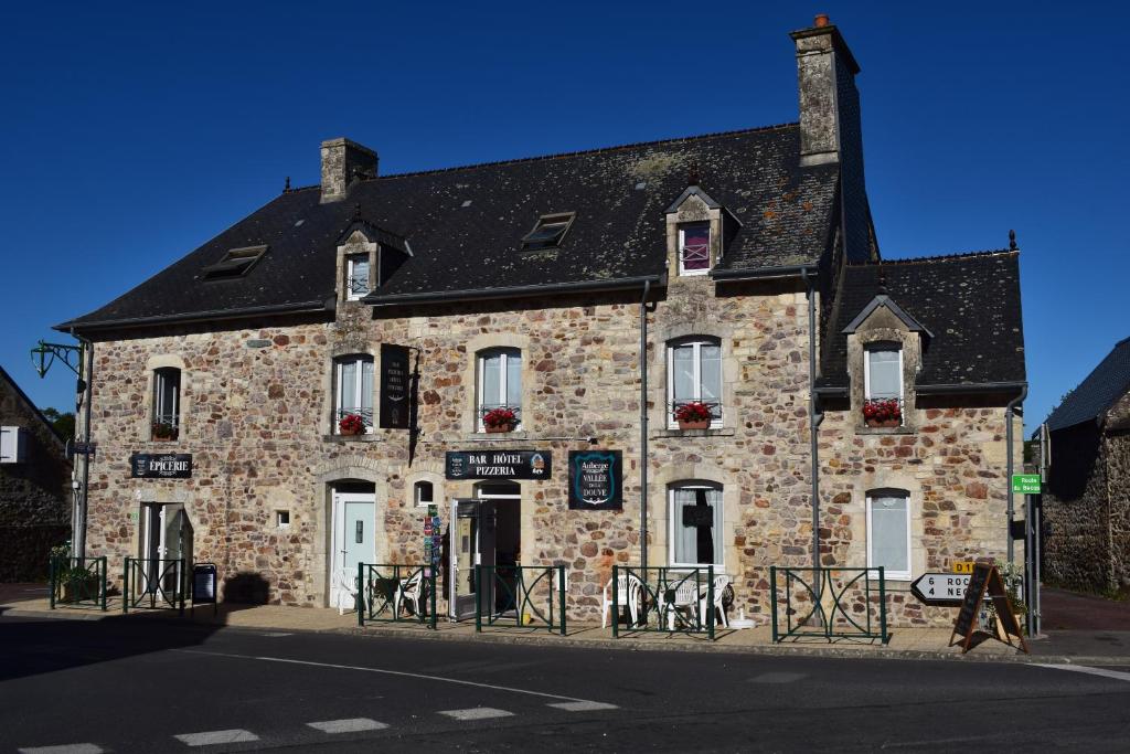 an old stone building on the corner of a street at Auberge de la vallée de la douve in L'Etang-Bertrand