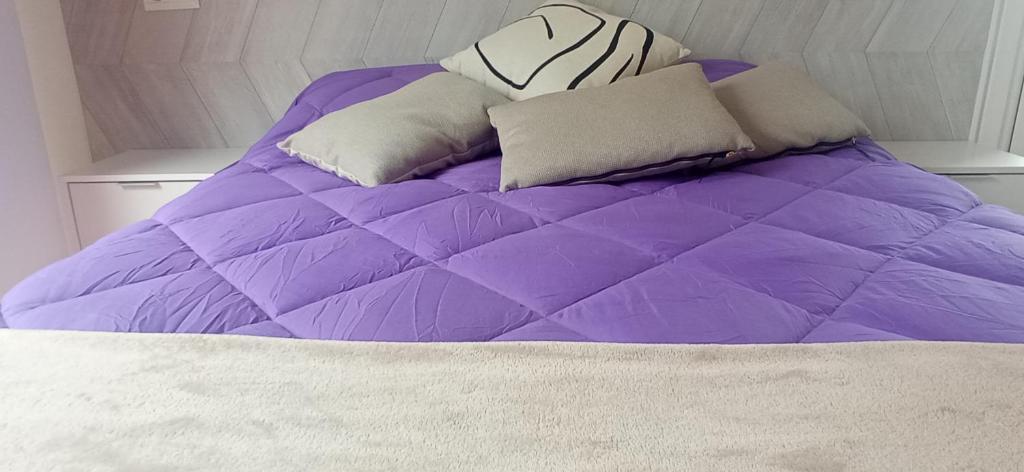edredón púrpura y almohadas en la cama en DÚPLEX ÁTICO XANA FOZ con terraza 80 m2 privada y vistas a la ría, en Foz