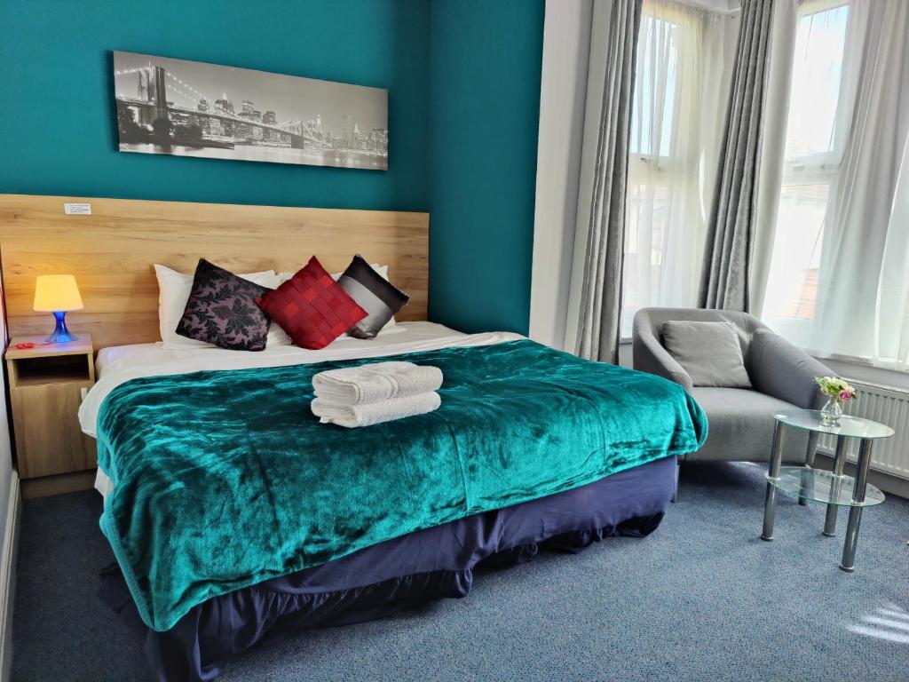 ein Schlafzimmer mit einem großen Bett und einem Stuhl in der Unterkunft Wellesley Hotel in Ilford