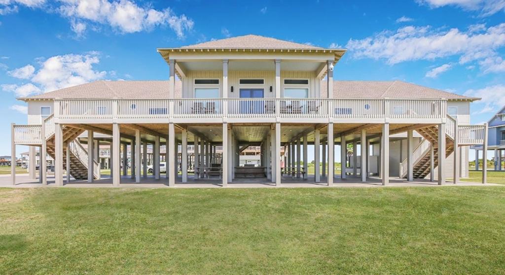 ein großes Haus mit einer großen Terrasse auf einem Rasen in der Unterkunft Sandy Orchid Lodge Home in Crystal Beach