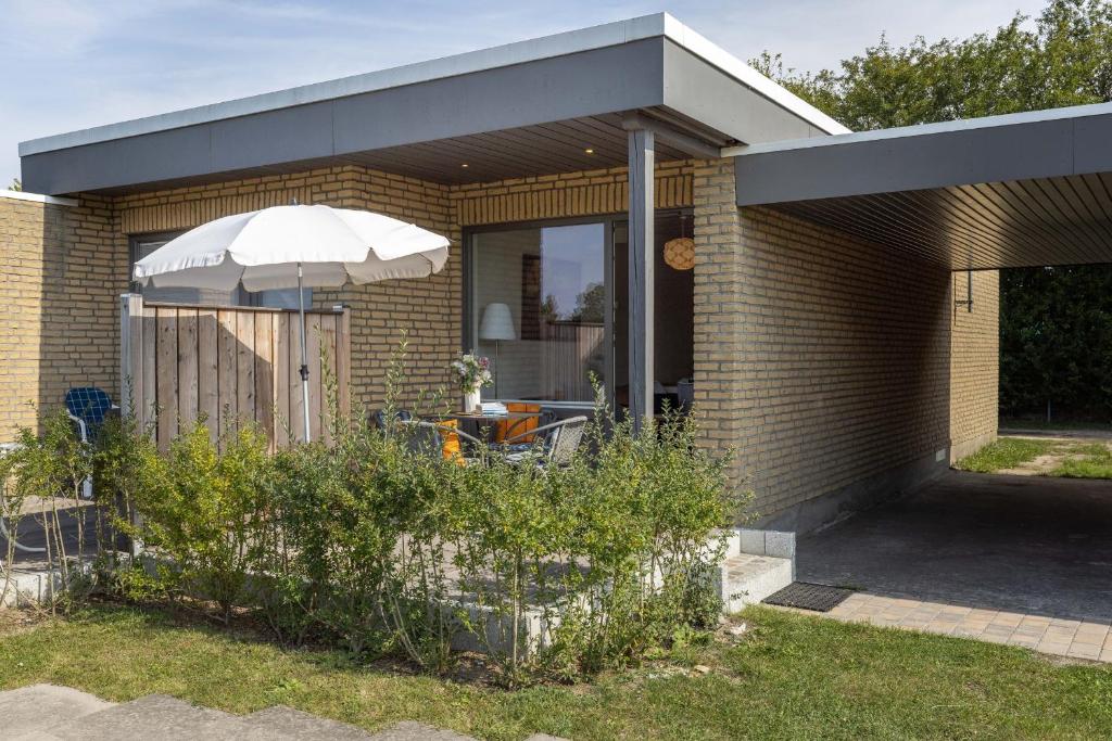 a brick house with an umbrella in a yard at Blankwasserweg 131 Lensterstrand Oase Bungalow 6 in Lenste