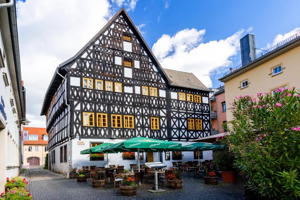 ワイマールにあるWatzdorfer Geleitschenke und Herbergeのテーブルと傘が置かれた白黒の古い建物
