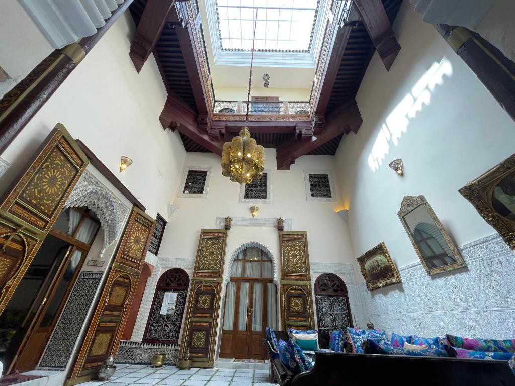 Riad Dar AlKATIB Meknès في مكناس: غرفة كبيرة بأبواب خشبية وثريا