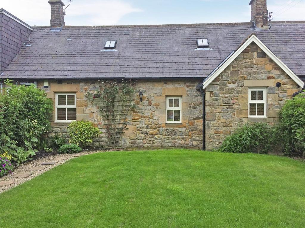 uma casa de pedra com um relvado verde em frente em Bumble Cottage em Newton on the Moor