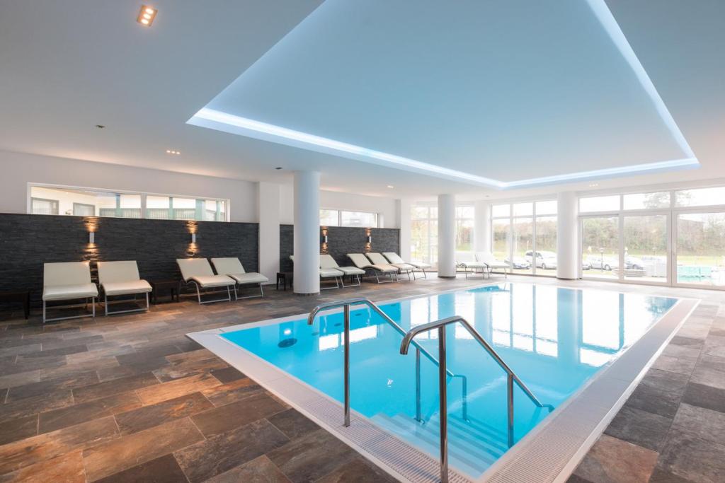 a large pool with chairs and tables in a building at Hotel Haus Tiefenbach in Bullange