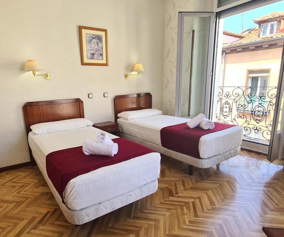 two beds in a room with a large window at Hostal Sardinero in Madrid