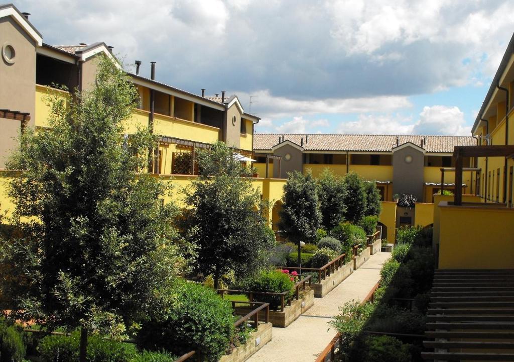a courtyard of a building with trees and bushes at Appartamenti e Affittacamere Le Due Ruote in Alberese